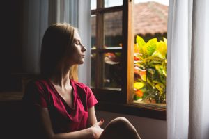 Woman relaxing while looking out window into garden.